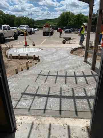 A group of construction workers are working on a concrete walkway.