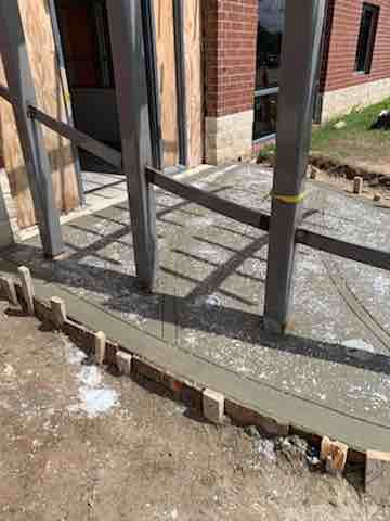 A concrete walkway is being built in front of a brick building.