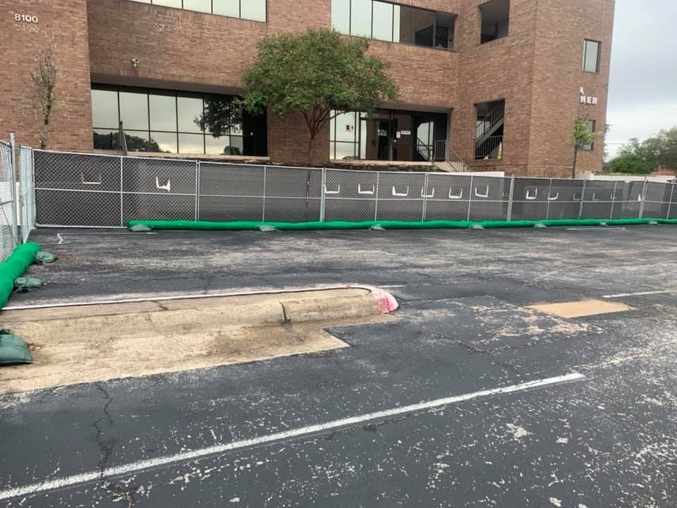 A fence is surrounding a parking lot in front of a brick building.