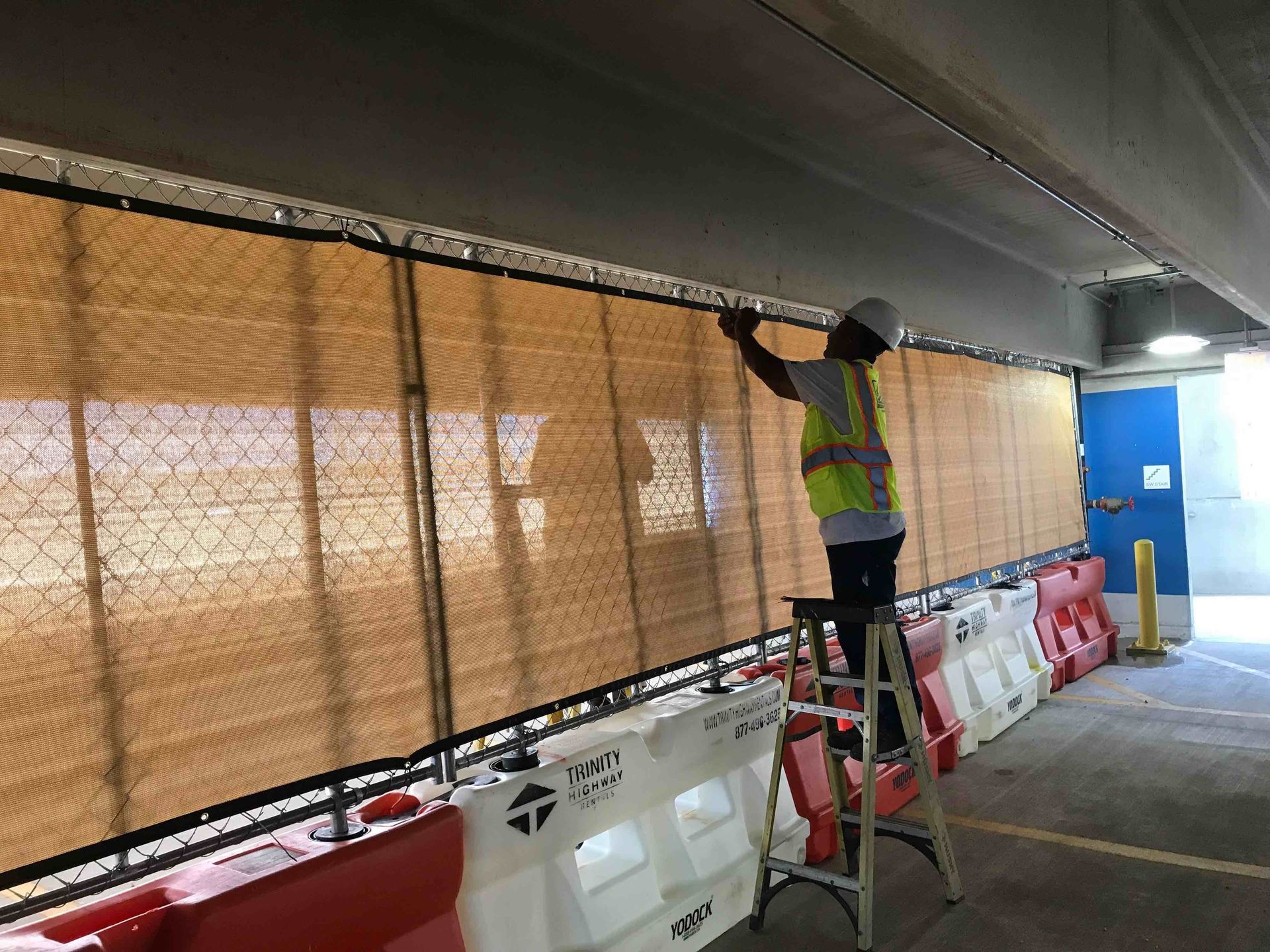 A man is standing on a ladder installing panel fencing