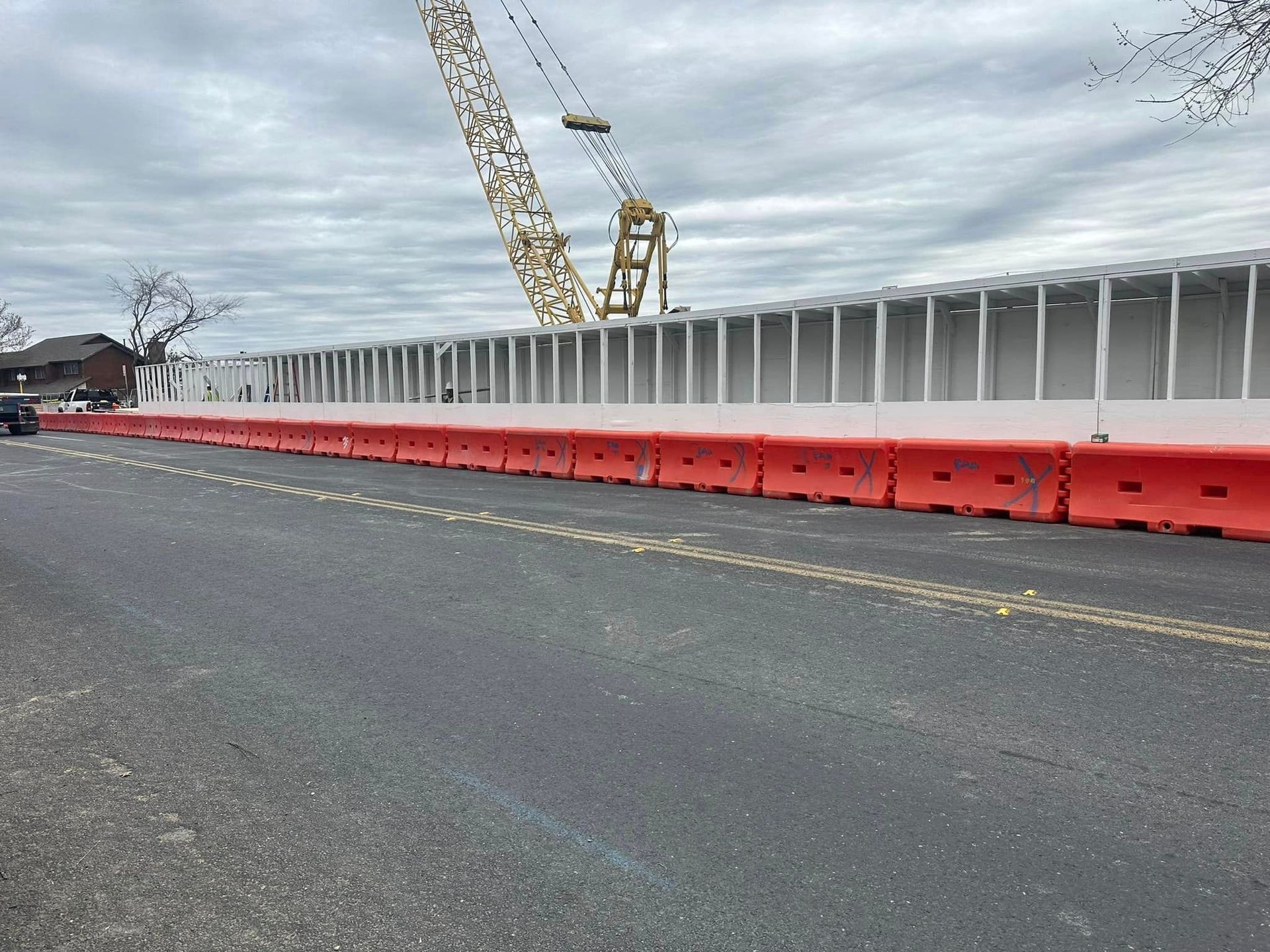 A safety pedestrian walkway is being built with a crane in the background.