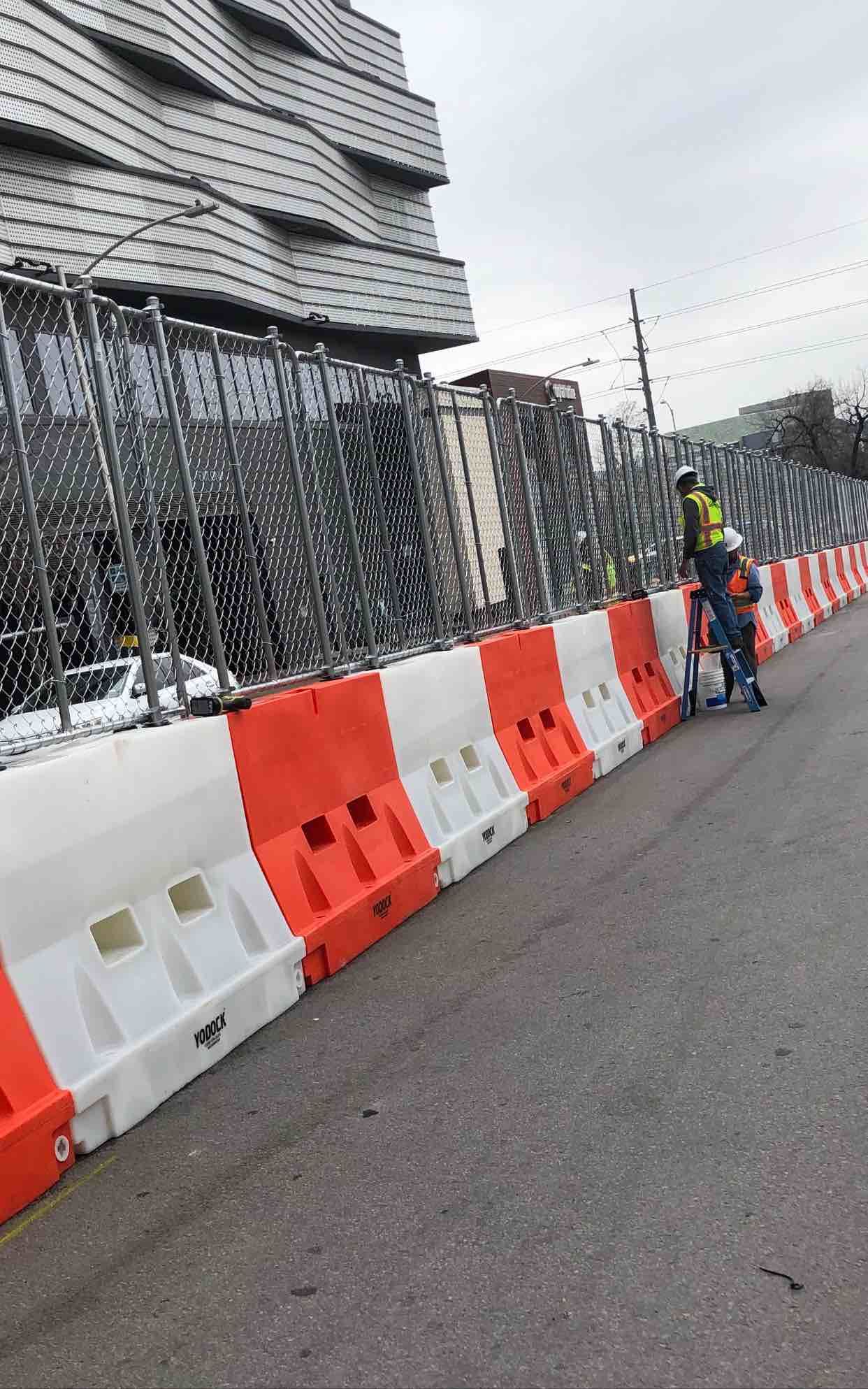 A man is riding a scooter next to a road barrier.