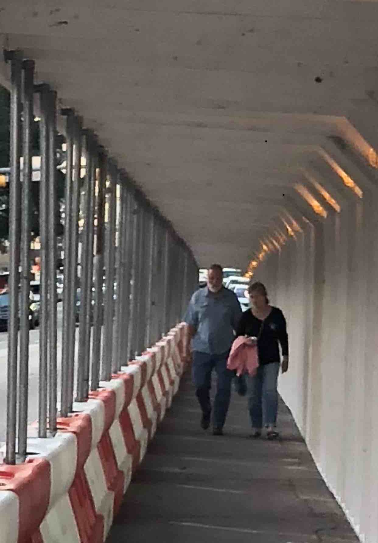 A man and a woman are walking through a safety pedestrian walkway
