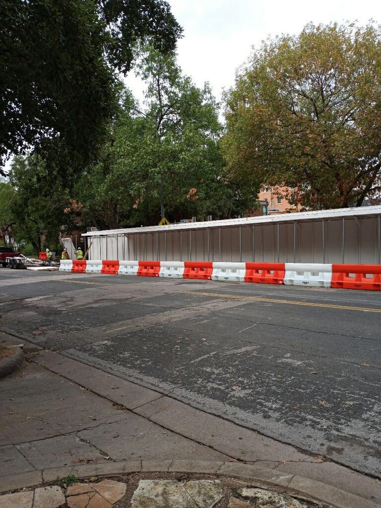 A row of water filled barriers on the side of a road.