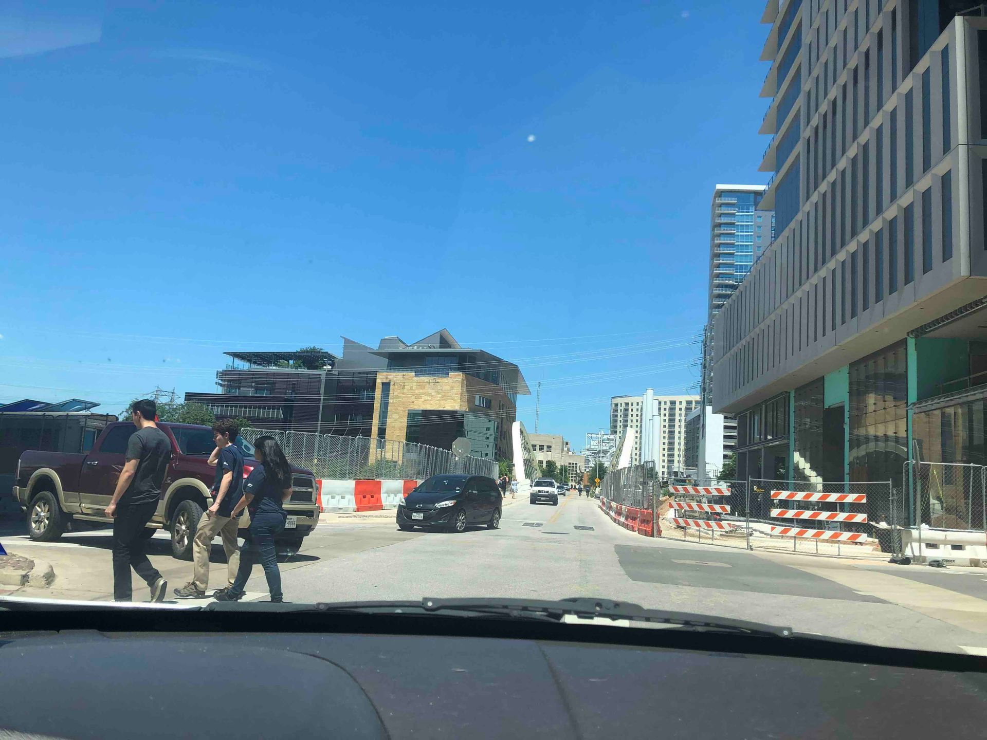 A group of people are walking down a street in front of a building under construction.