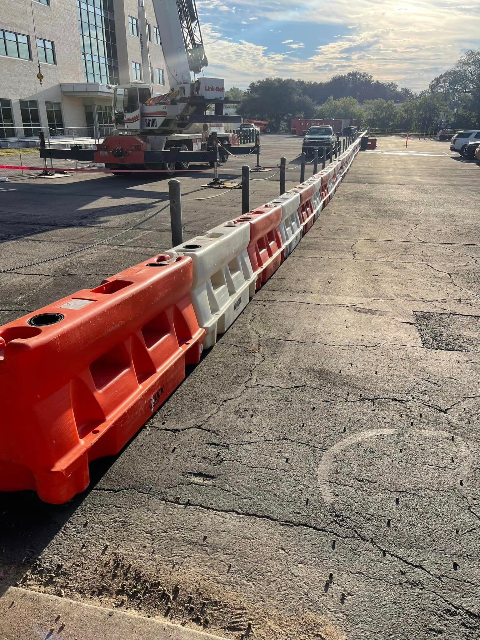 A long orange and white barrier is sitting on the side of a road.
