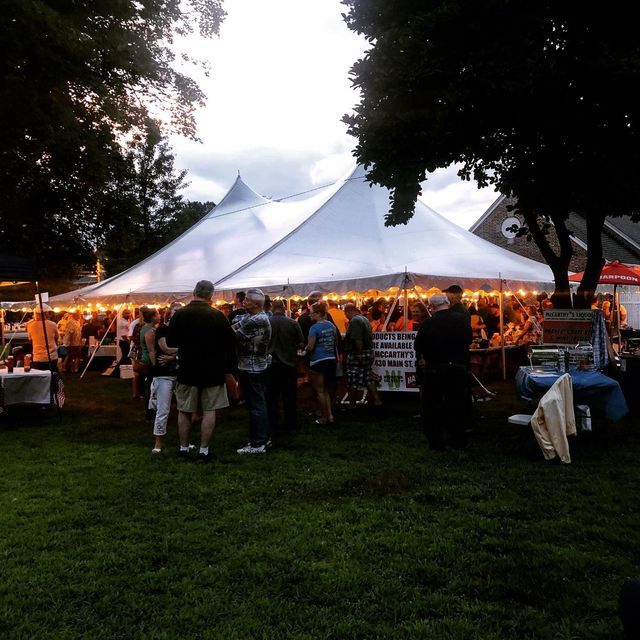 A group of people are gathered under a white tent