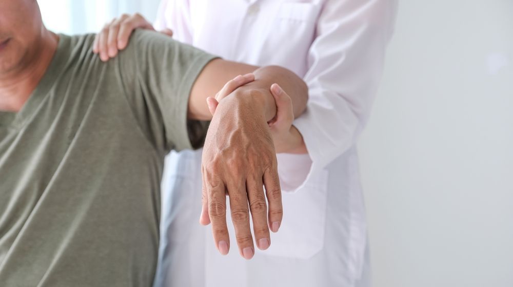 Female doctor performing hand rehab in physical therapy session.