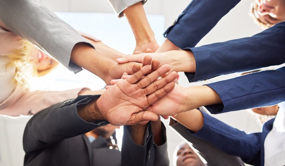 Group of people putting their hands in a circle.