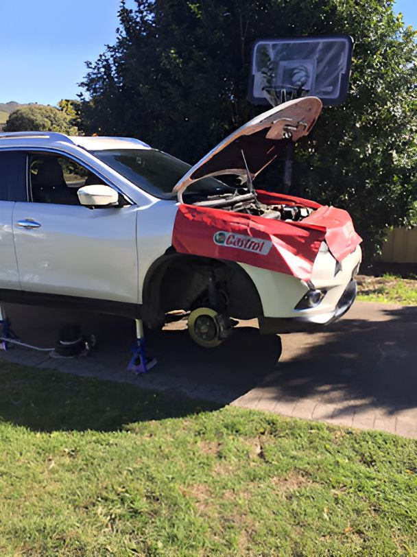 A White Car With the Hood Open is Parked in a Driveway — Coffs Coast Mobile Mechanical in Toormina, NSW