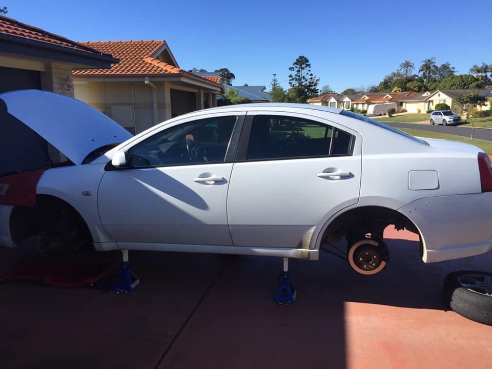 A White Car With the Hood Up is Parked in a Driveway — Coffs Coast Mobile Mechanical in Toormina, NSW