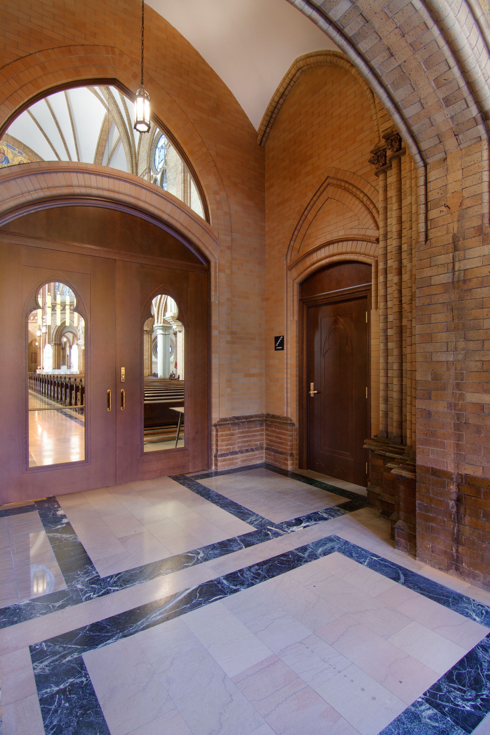 Interior entryway with marble floor, arched doorways, and wood doors.