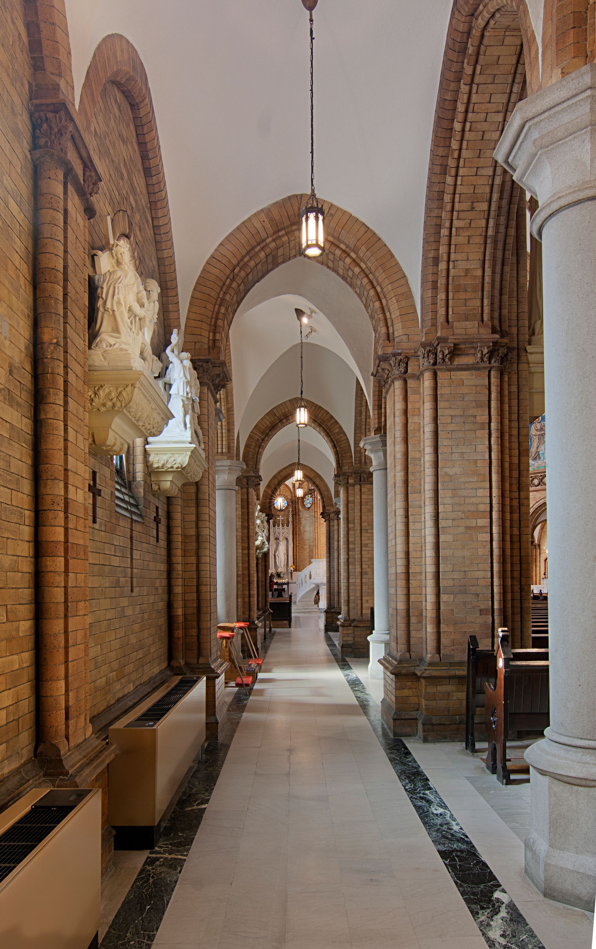 Long hallway of a church with arched ceiling, brick walls, and decorative pillars.