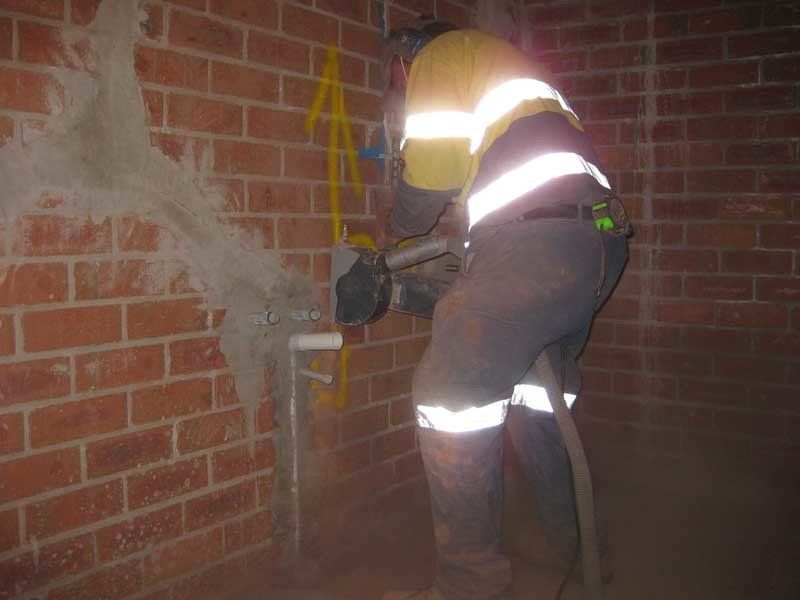 Man sawing brick wall