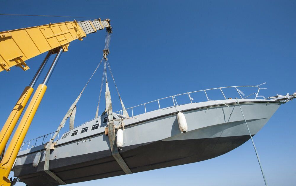 A Boat Is Being Lifted By A Large Yellow Crane — J & D Rigging Pty Ltd In Bohle, QLD