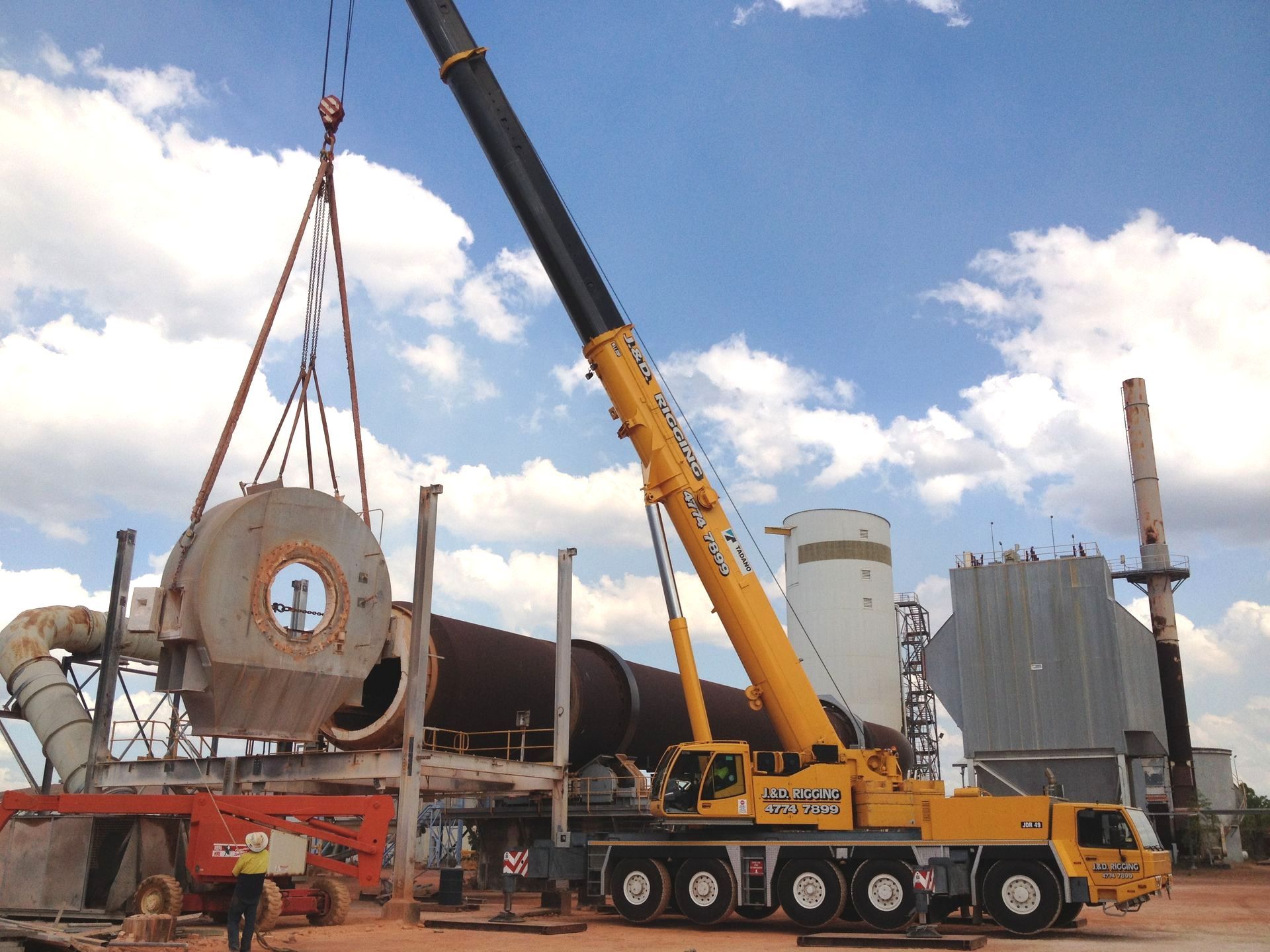 An Orange Truck With A Crane Attached To It Is Parked In Front Of A Building — J & D Rigging Pty Ltd In Bohle, QLD