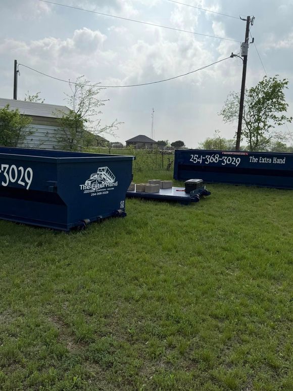 A couple of dumpsters are sitting on top of a lush green field.