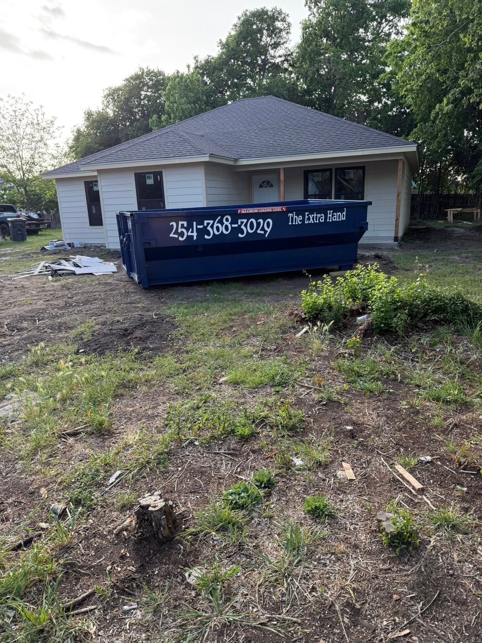 A dumpster is sitting in front of a house that is being remodeled.