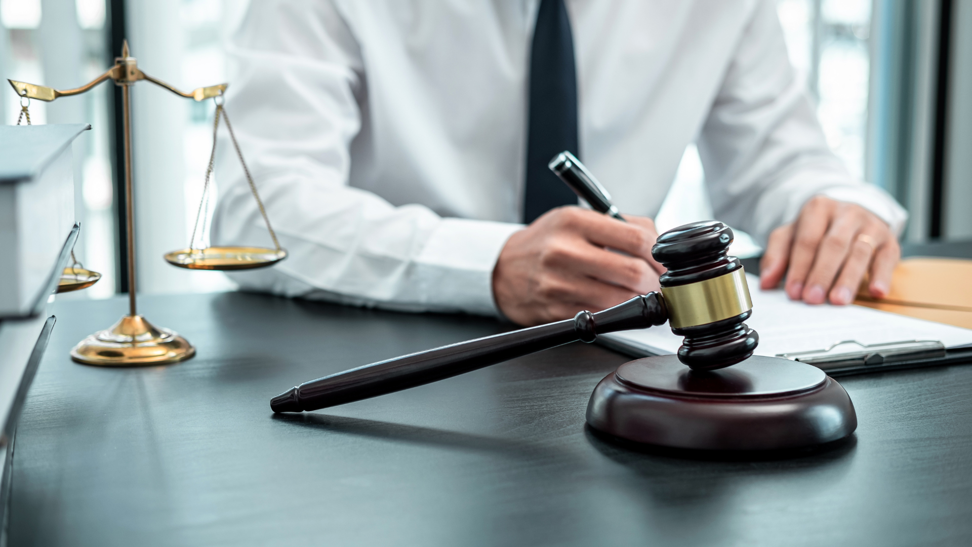 A judge is sitting at a desk with a gavel and scales of justice.