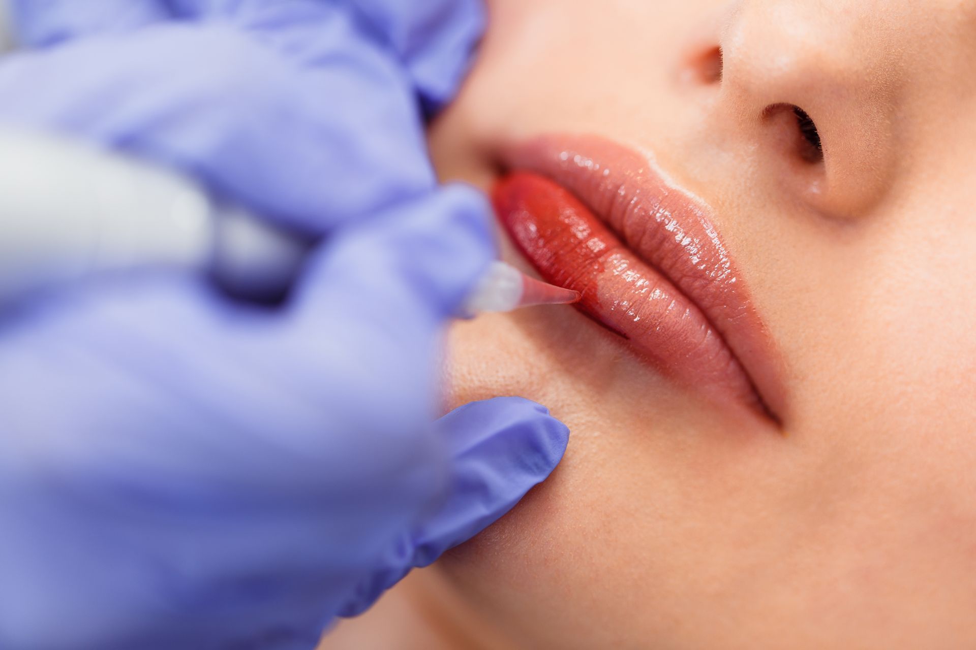 a woman is getting a permanent lip tattoo on her lips .