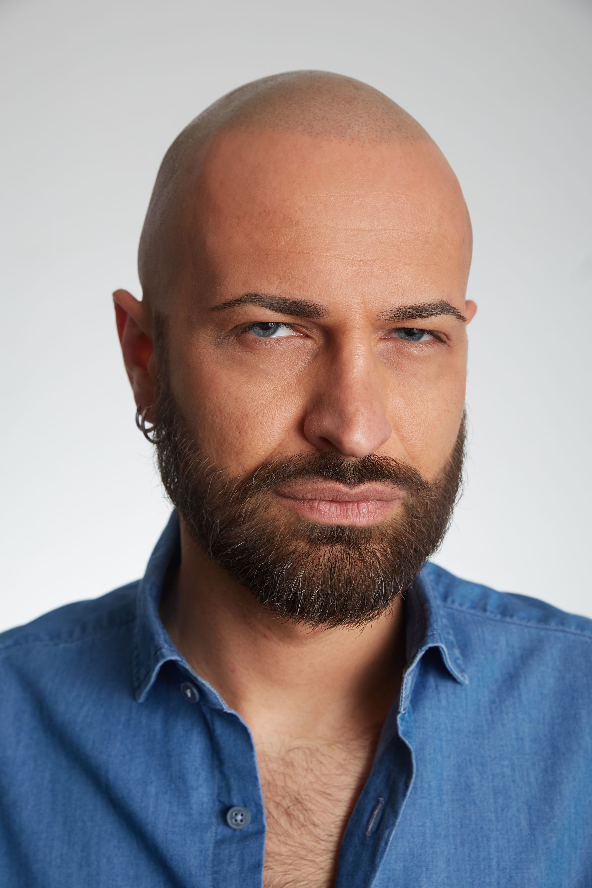 a bald man with a beard is wearing a blue shirt .