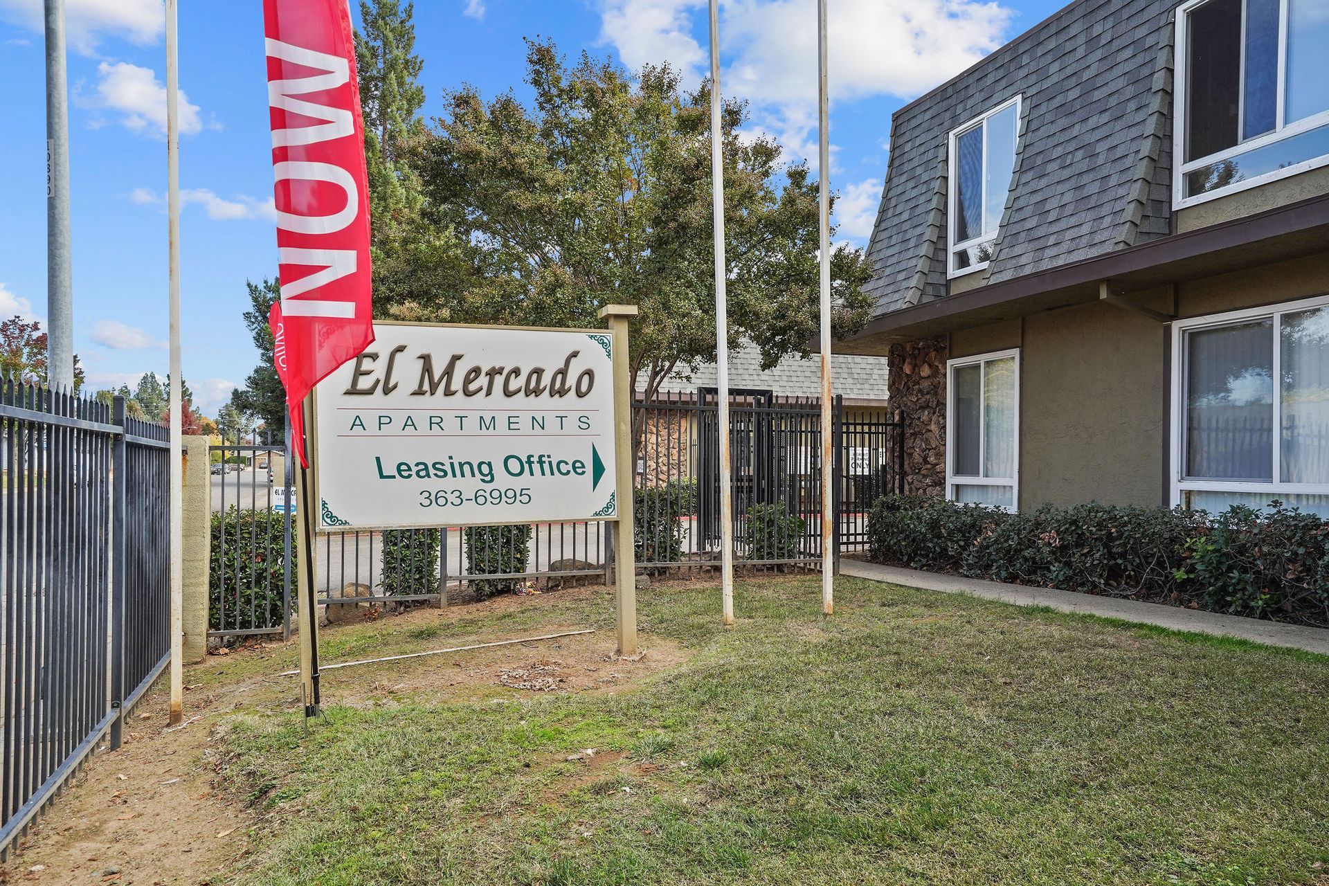 El Mercado leasing office sign beside a townhouse courtyard and lawn