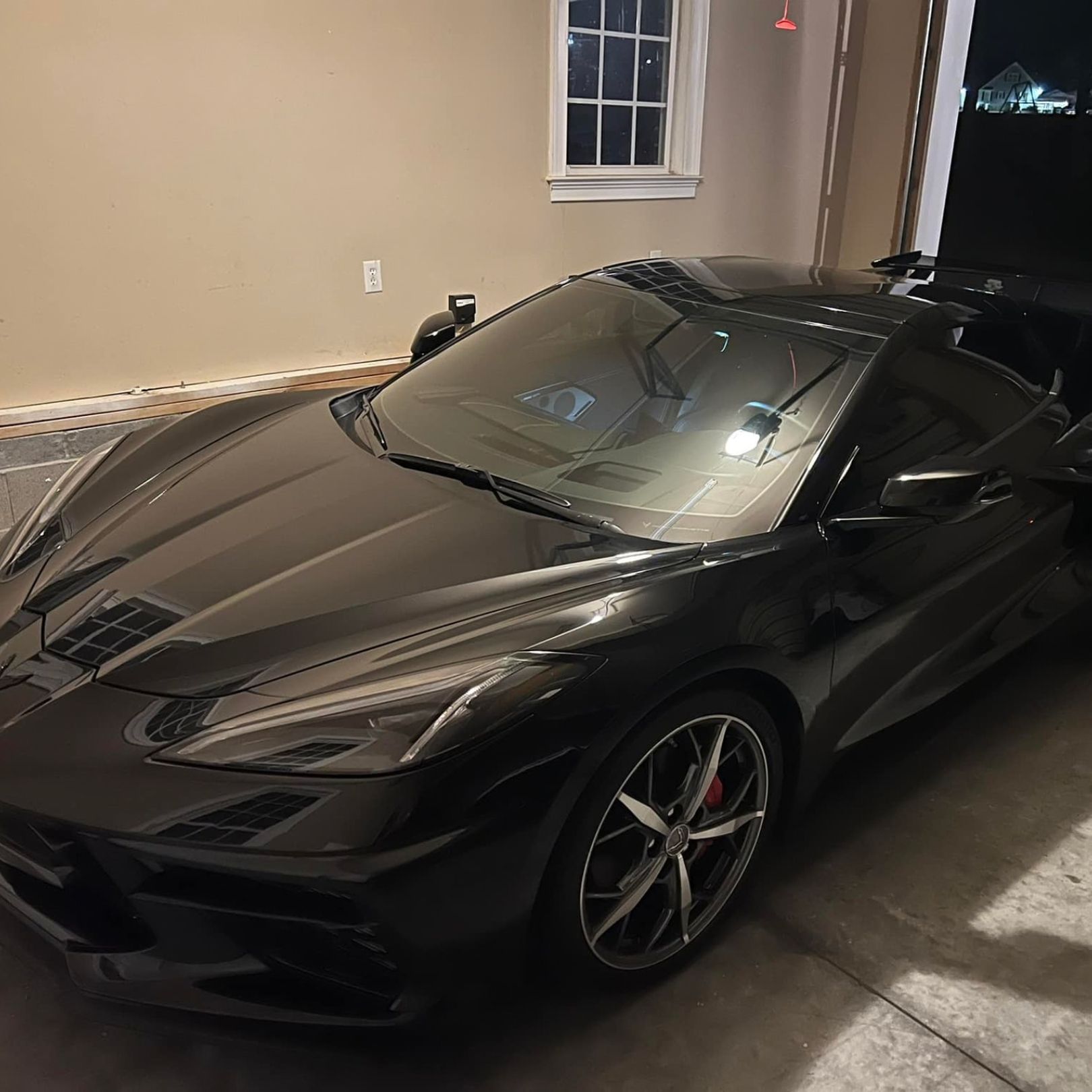 A black Chevrolet Corvette C8 parked inside a garage at night.
