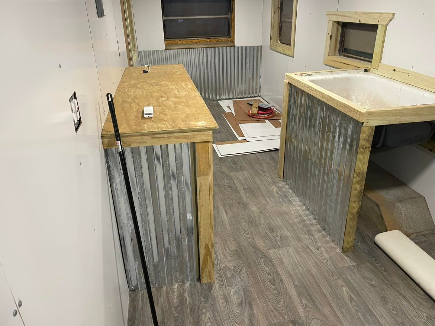 An interior view of a room under construction featuring wood-topped counters, corrugated metal siding, and wood flooring.