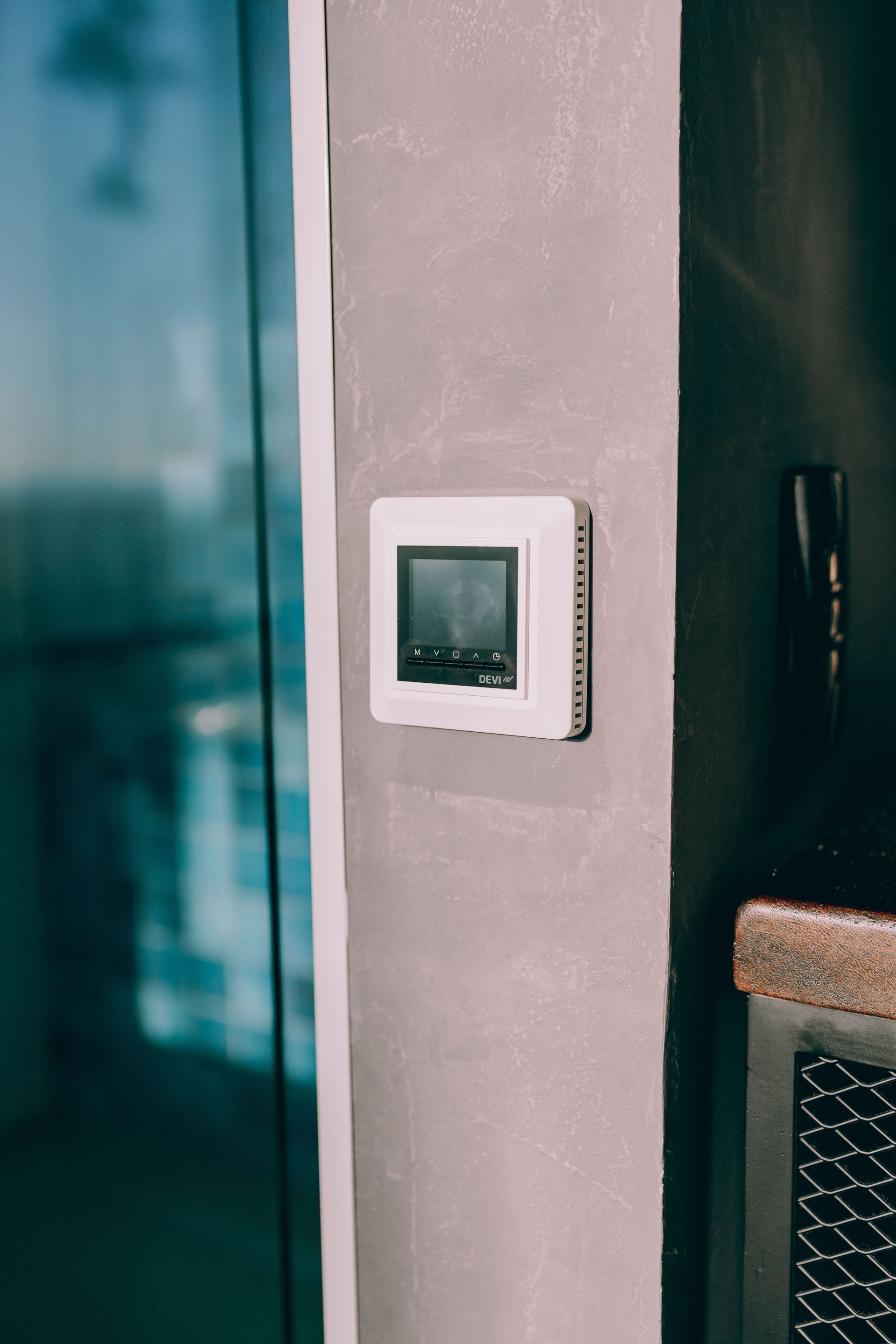 Wall-mounted digital thermostat beside a doorway on a gray wall