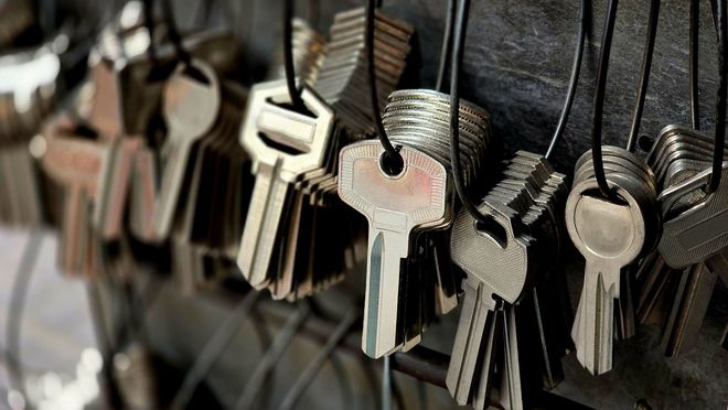 A bunch of keys hanging from a string on a rack.