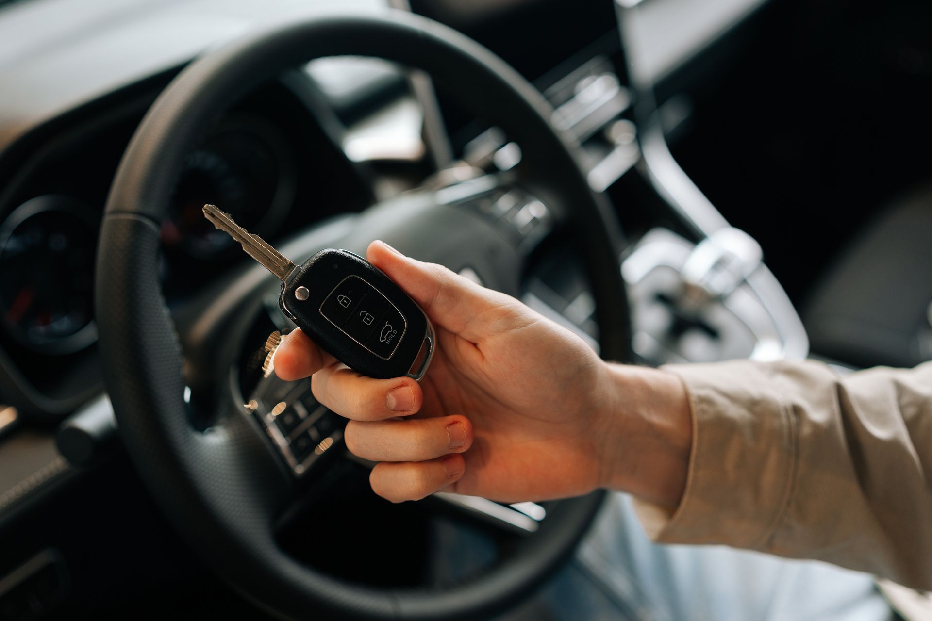 A person is holding a car key in their hand in a car.