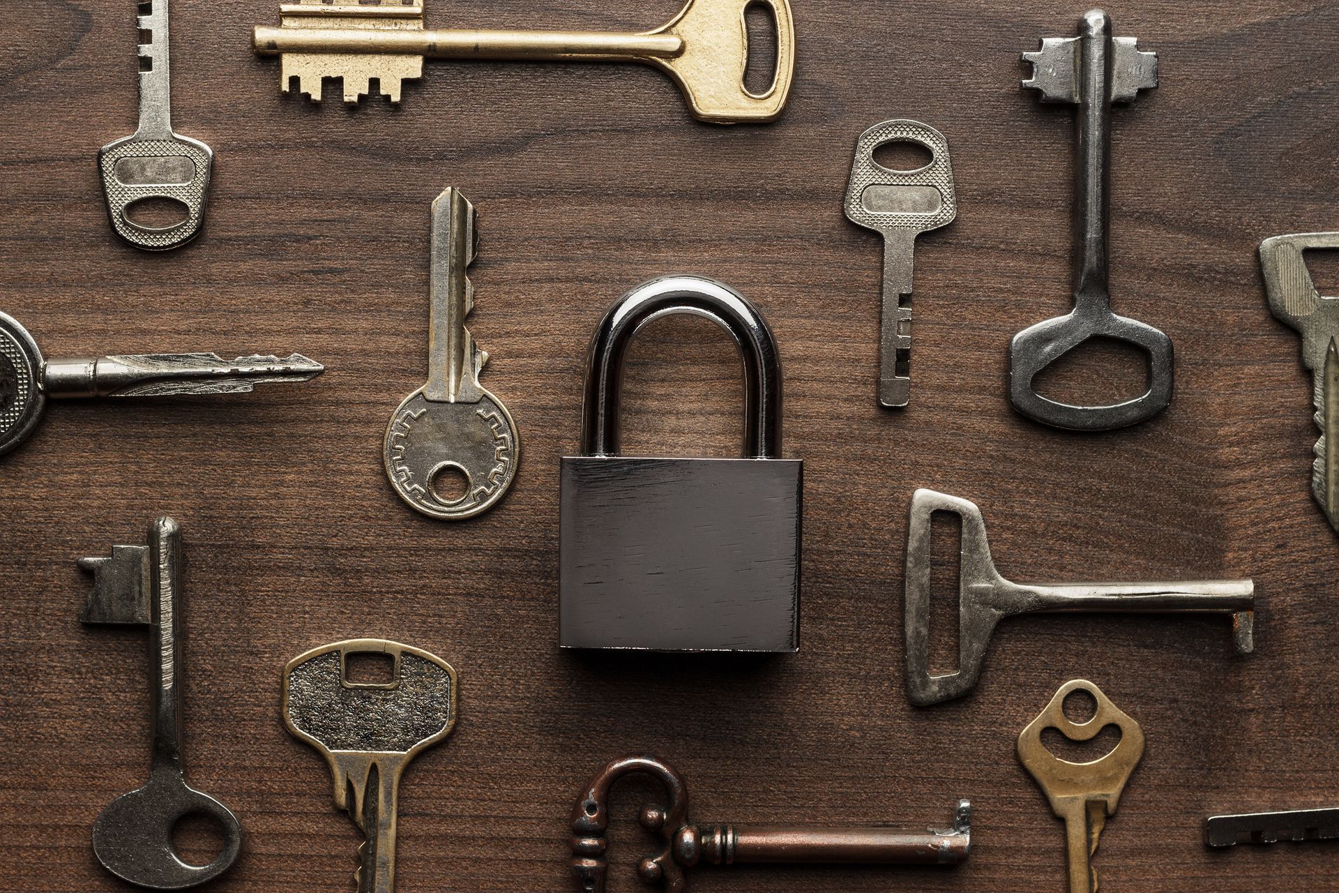 A bunch of keys and a padlock on a wooden table.