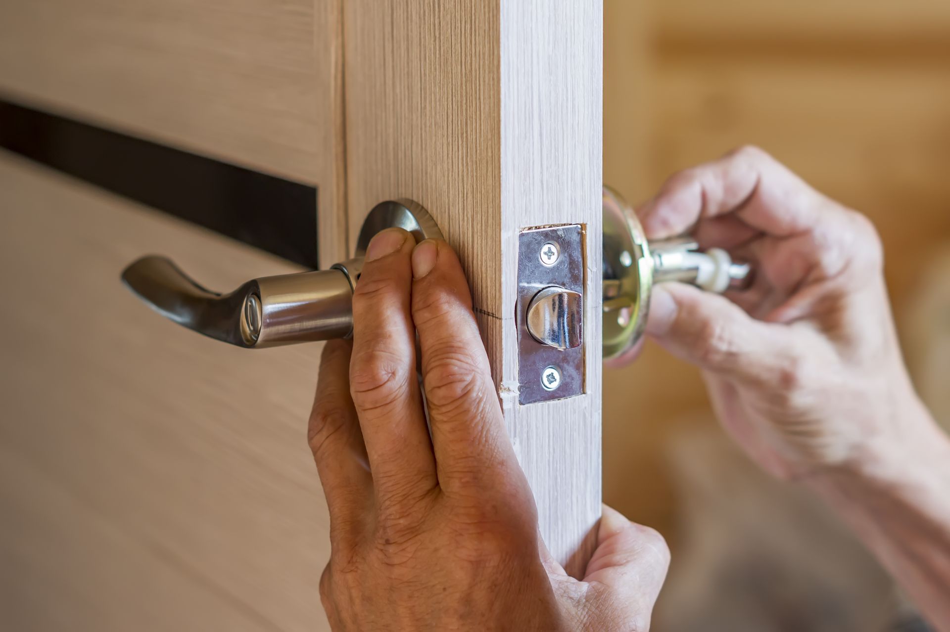 A person is installing a door handle on a wooden door.