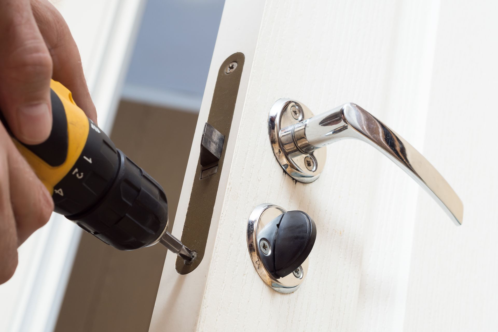 A person is fixing a door with a drill.