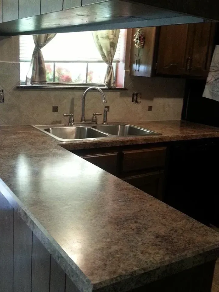 Kitchen with a double sink, brown countertops, and a window with curtains.