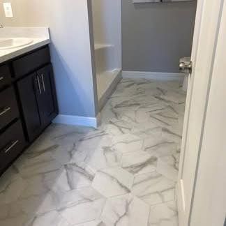Bathroom with white hexagonal marble-patterned tile flooring, dark brown cabinets, and a gray wall.