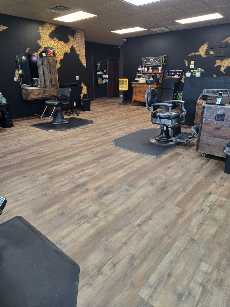 Barbershop interior with two chairs, wood-look flooring, black walls, and decorative map.
