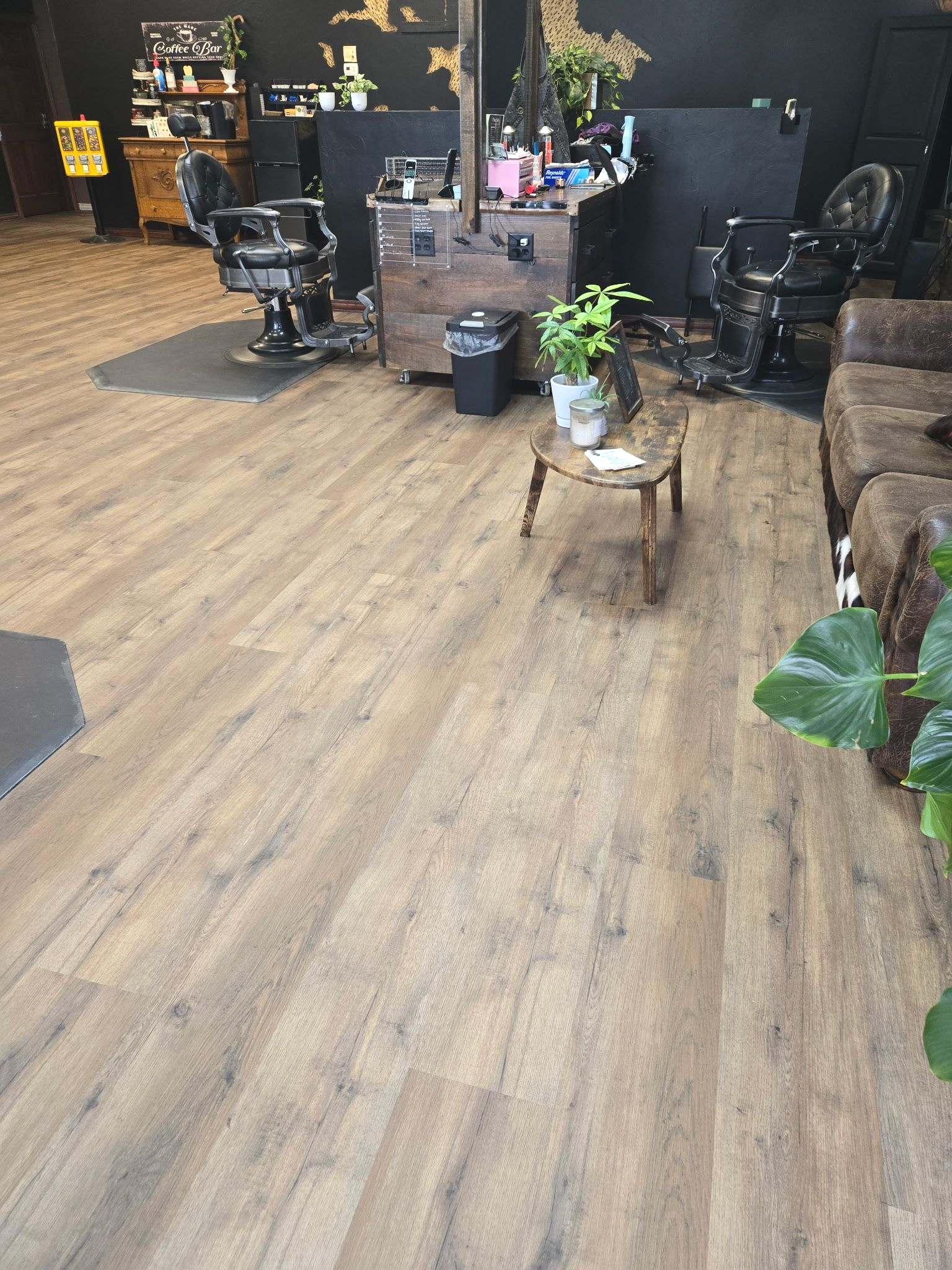 A barber shop interior with wooden floors, chairs, and styling stations.