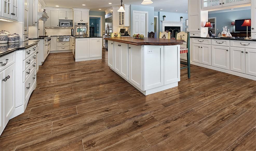 Spacious kitchen with white cabinets, a dark wood island, and wood-look tile flooring.