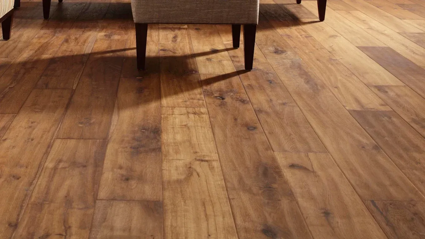 Wooden floor with chair legs casting a shadow. The floor has a warm, brown tone.