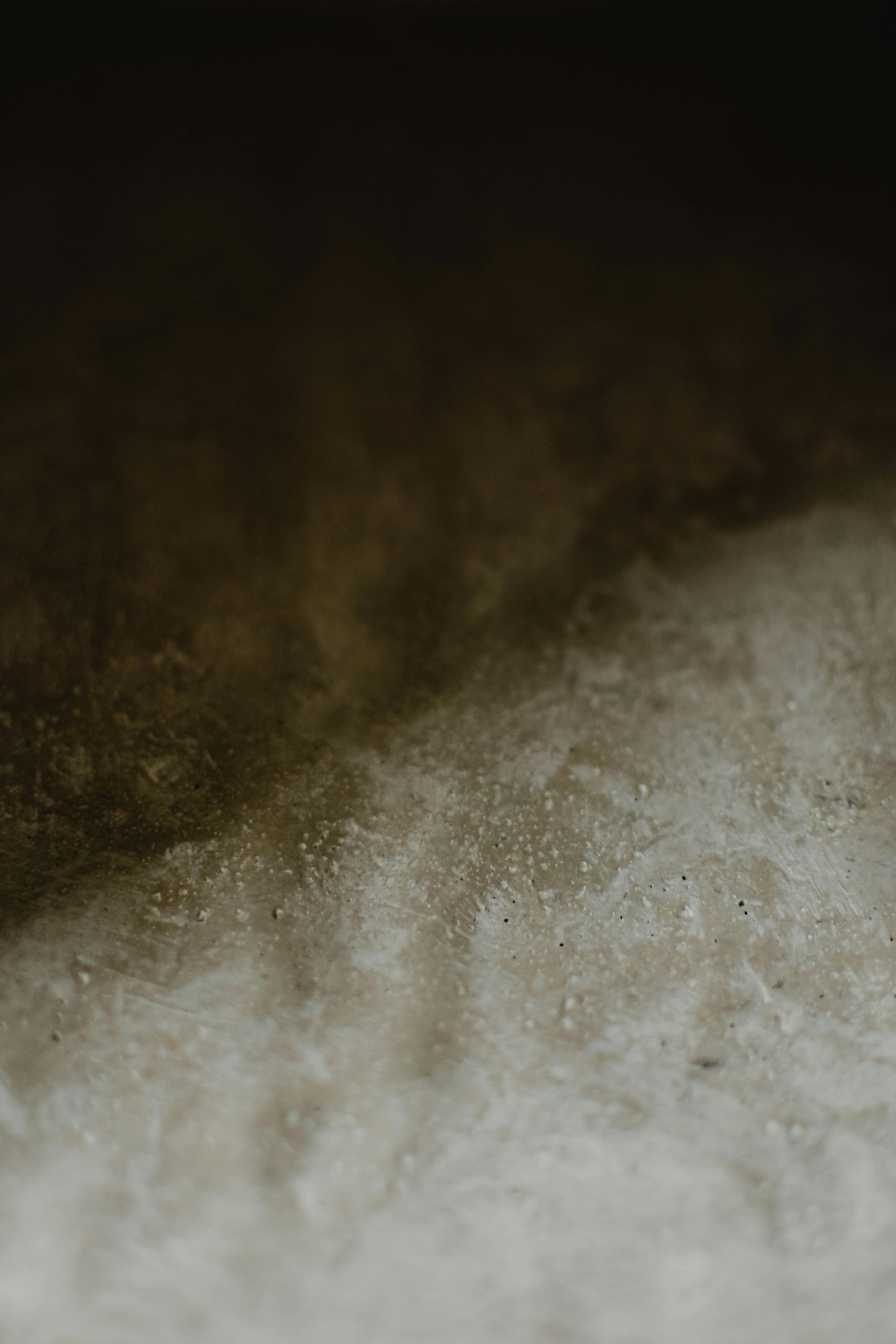 Close-up of a textured surface with a diagonal split between a dark, shadowy area and a lighter, grainy area.