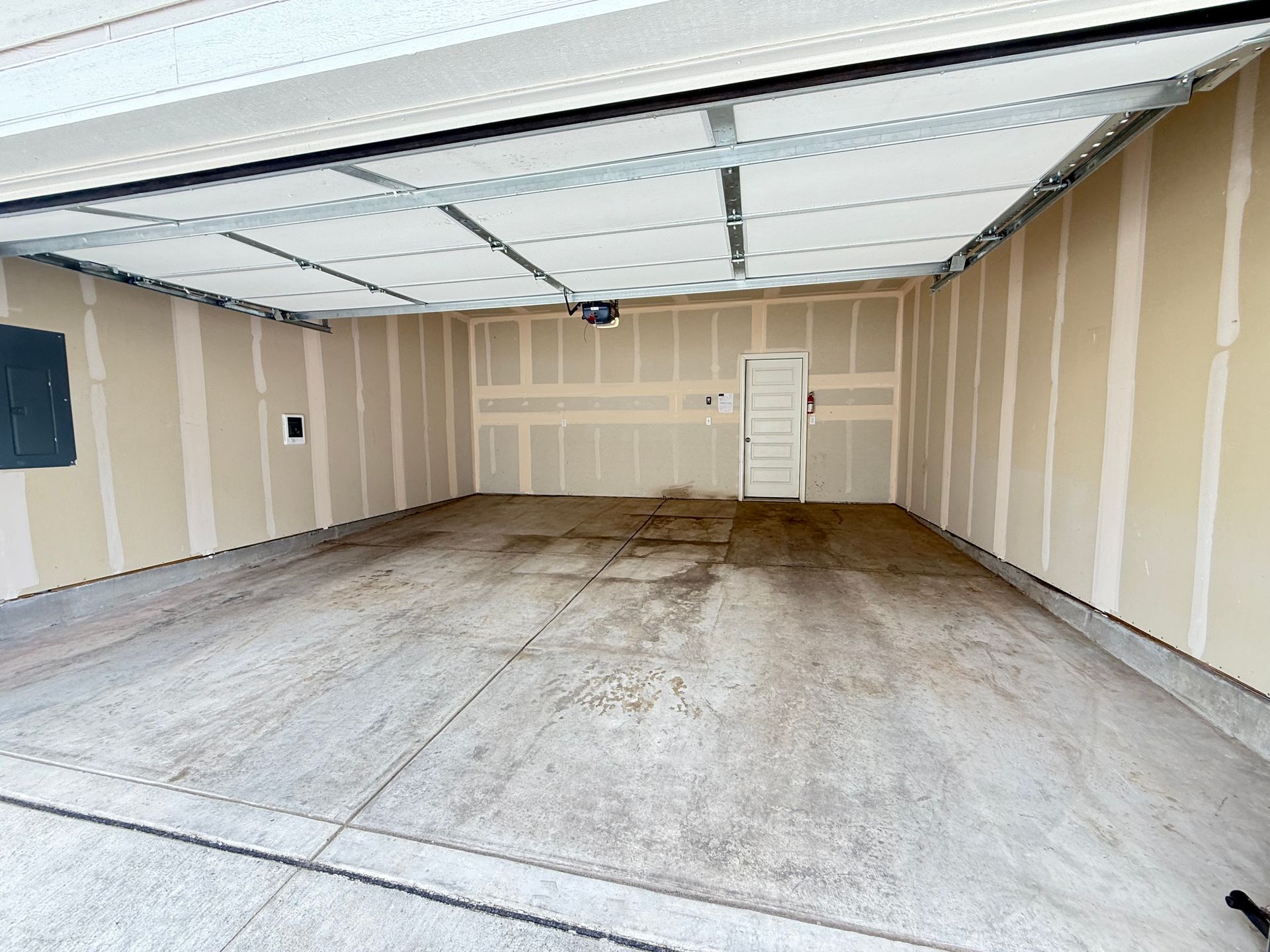 Empty garage interior with a concrete floor and unfinished drywall walls.