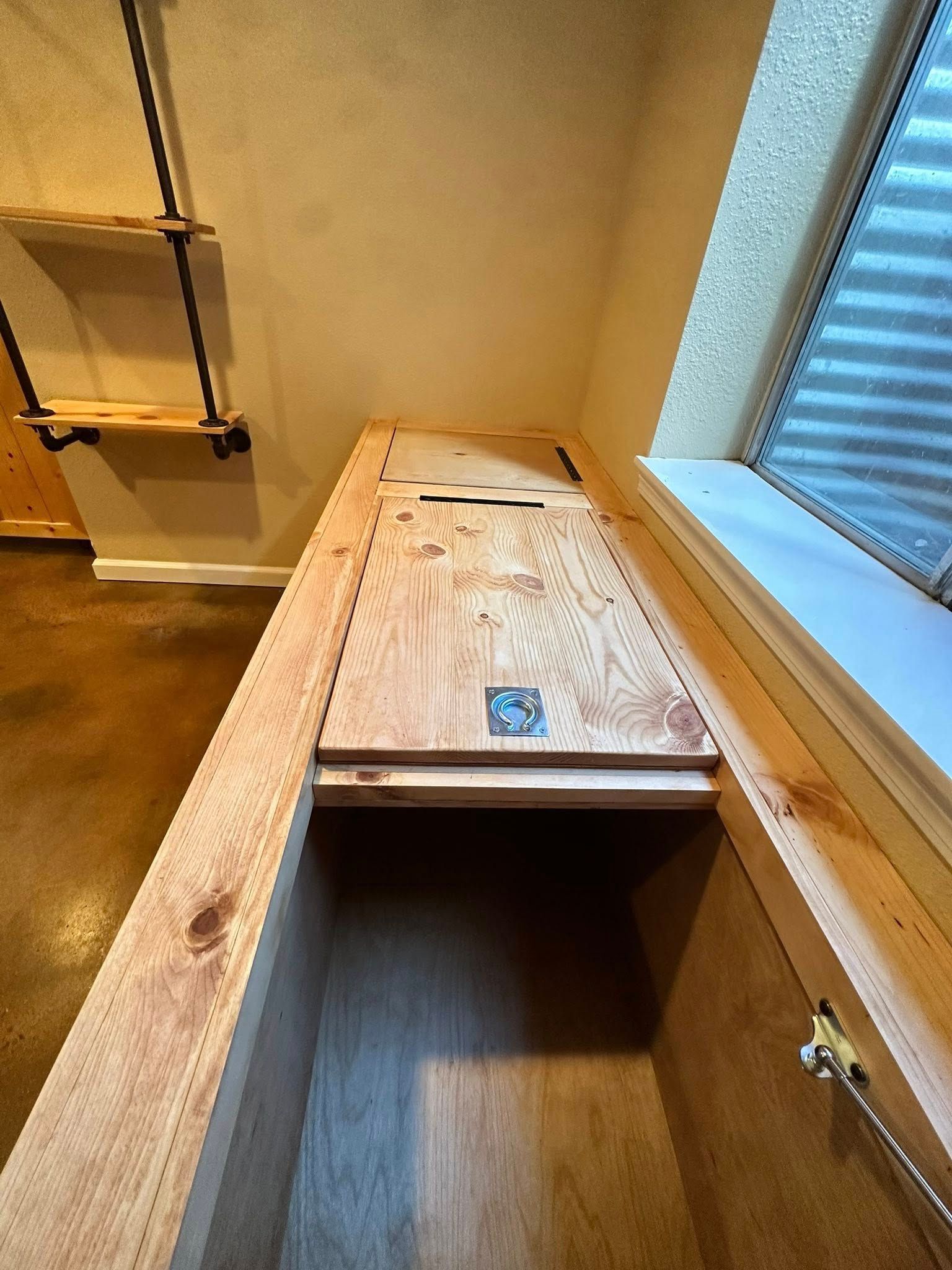 Open wooden storage chest with hinged lid, built-in under a window.