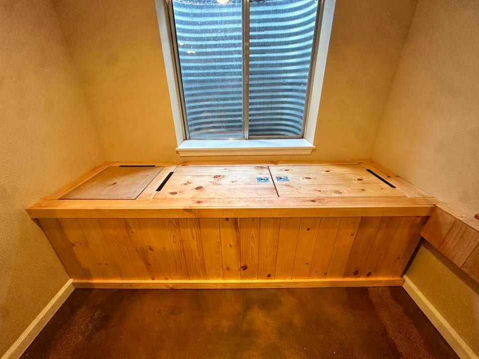 Wooden bench under a window with openable lids, inside a room with a window well.