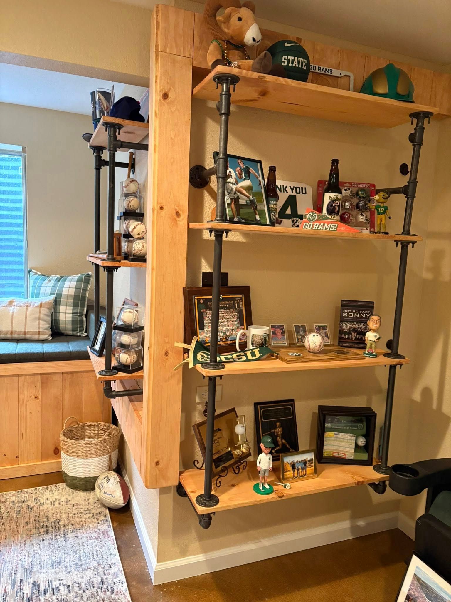Wooden shelves with black pipes against a tan wall, displaying various sports memorabilia.