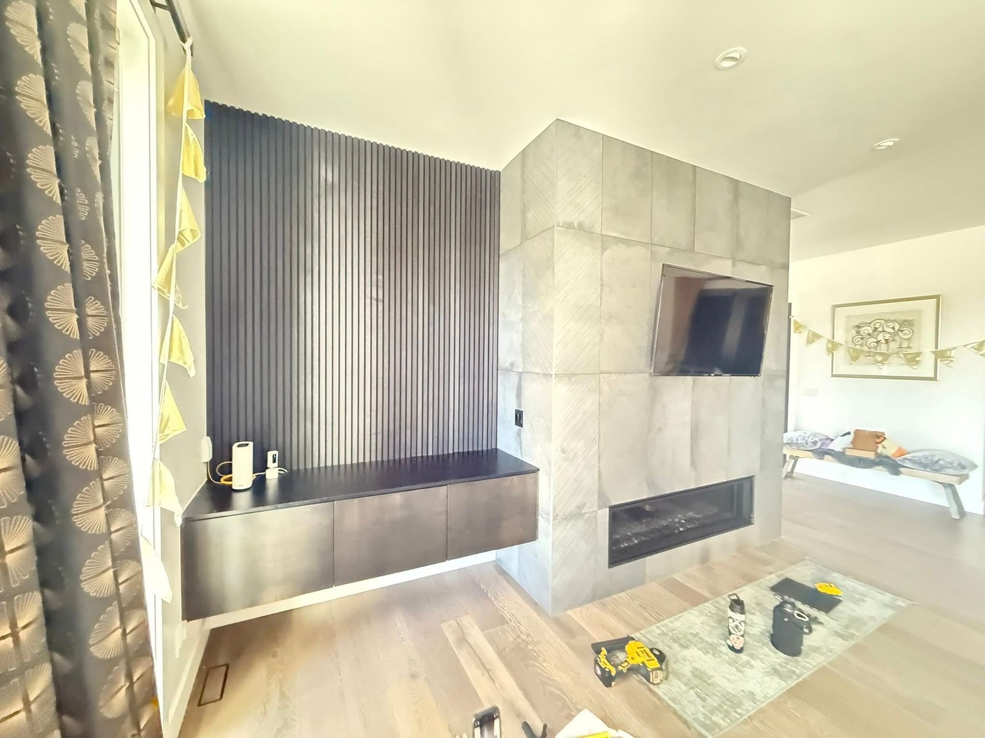 Modern living room with fireplace, built-in storage, and wood flooring. Grey, black and yellow tones.