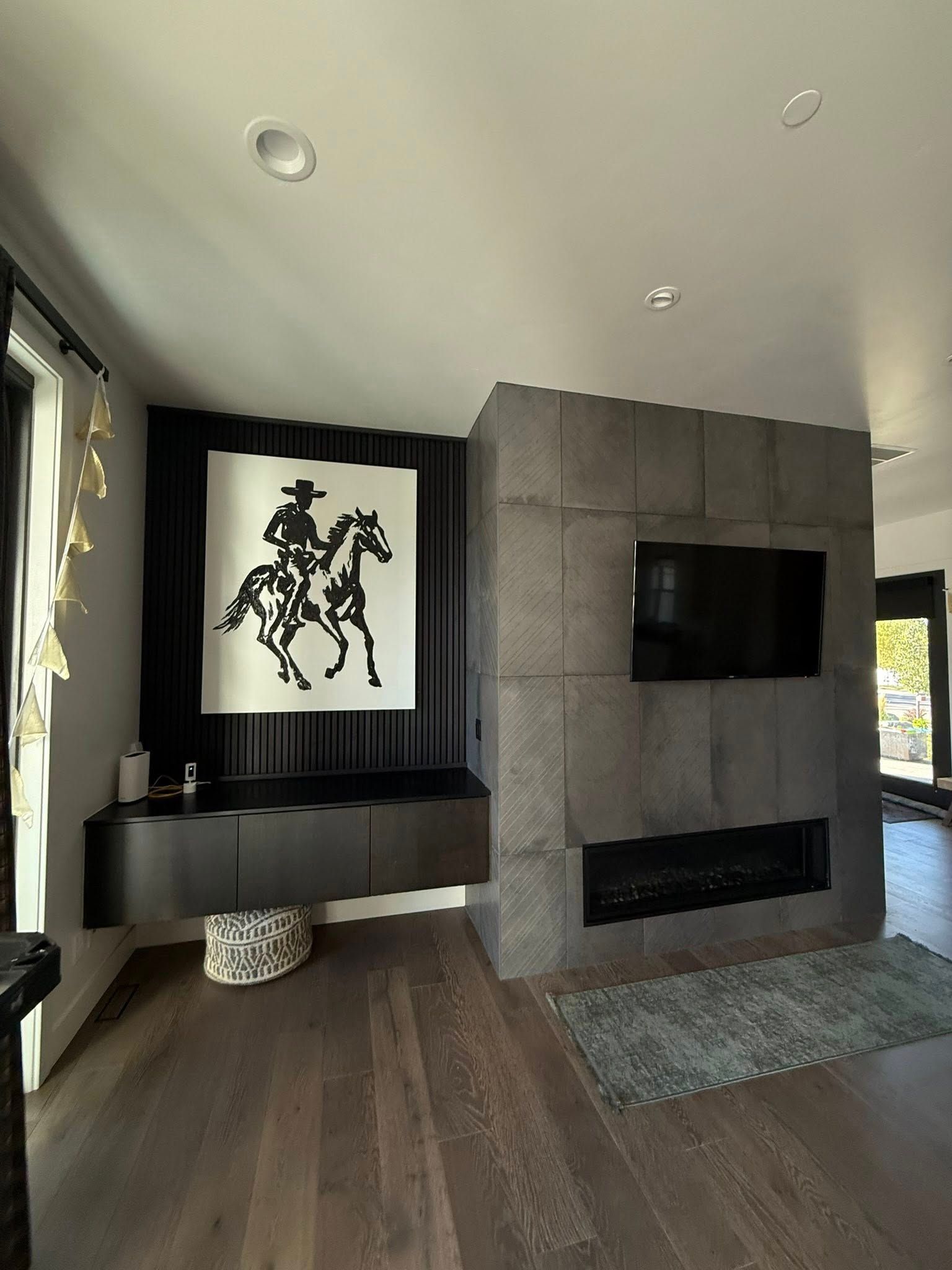Living room with a stone fireplace and black artwork of a cowboy on a horse.