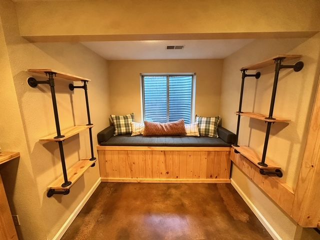 Cozy reading nook with built-in bench, wooden shelves, and window with blinds.