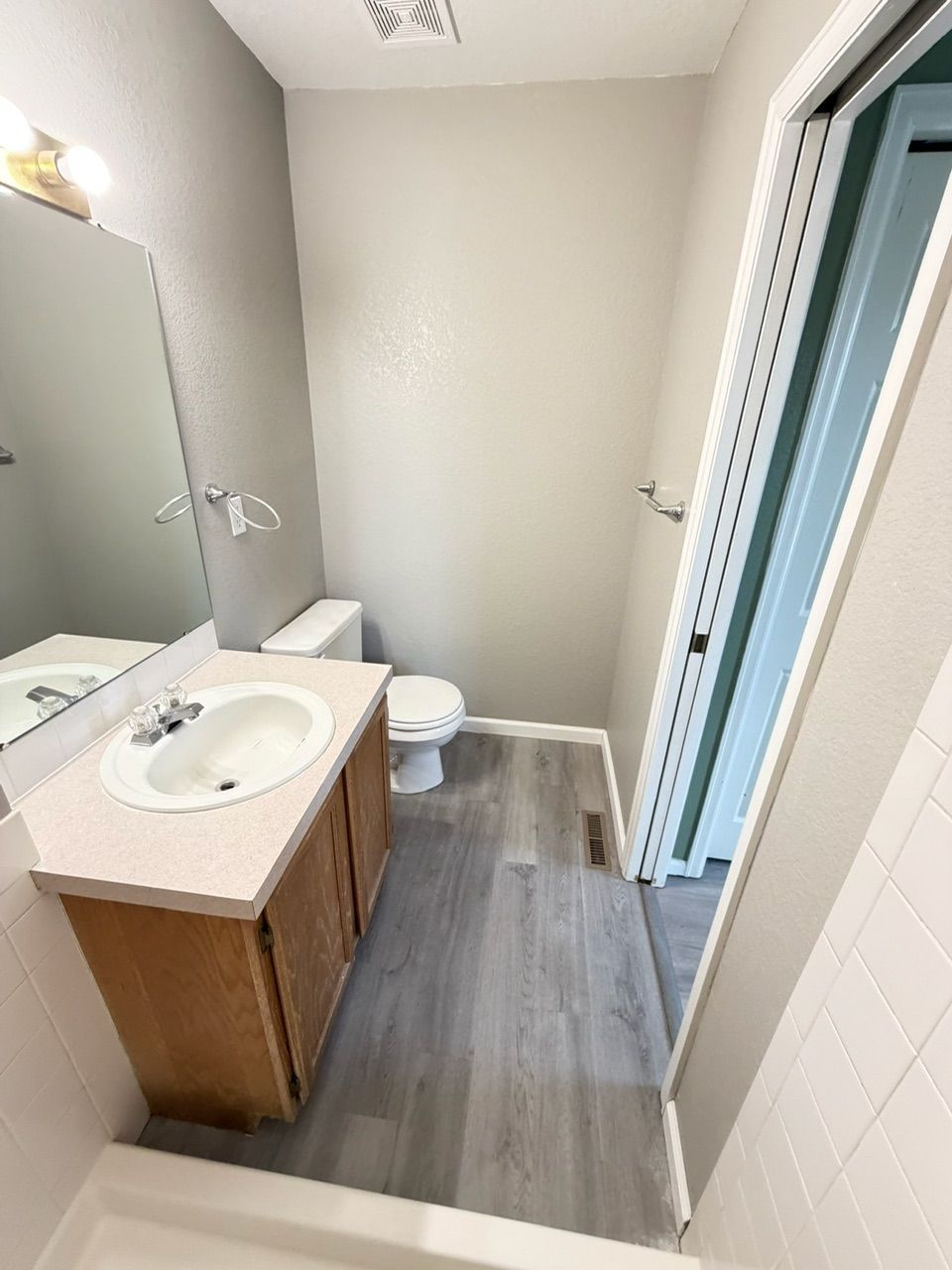 Bathroom with a white sink, toilet, and light gray walls and flooring.