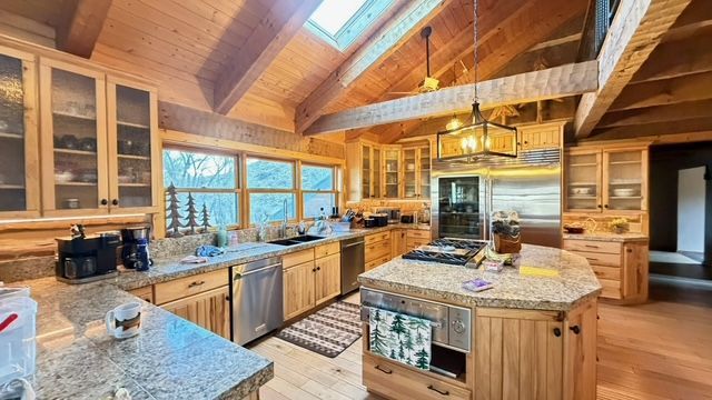 Rustic kitchen with wooden cabinets, granite countertops, and an island with a stovetop.